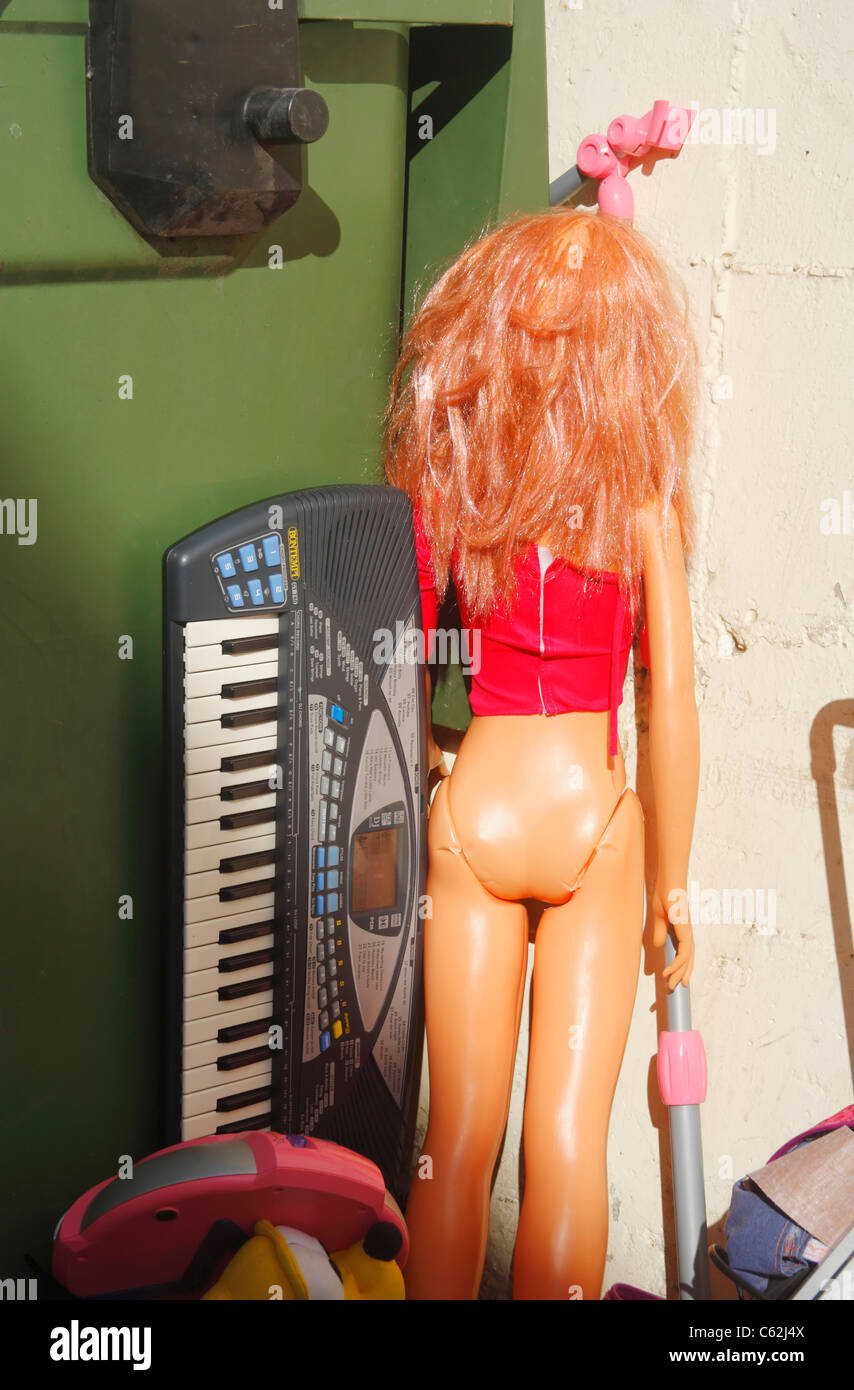 Bontempi keyboard and large doll next to rubbish container Stock Photo