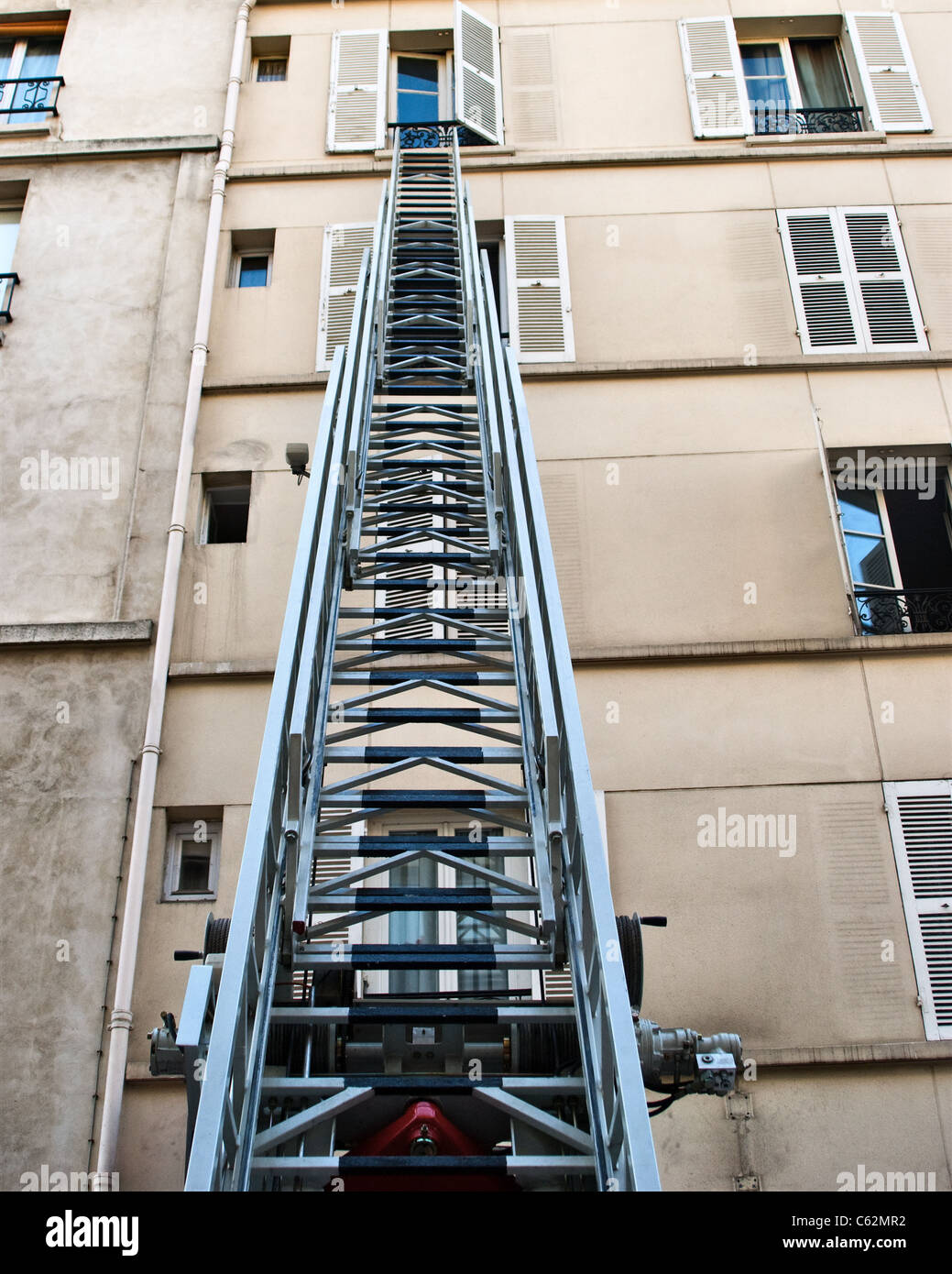 Extended fireman's (fire engine) ladder lift, up to an open window in a tower block Stock Photo