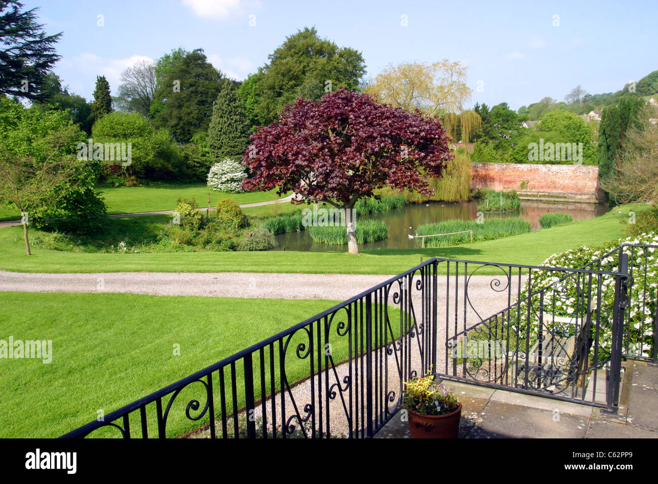 Large manicured lawned UK garden with trees, shrubs and large pond. Stock Photo