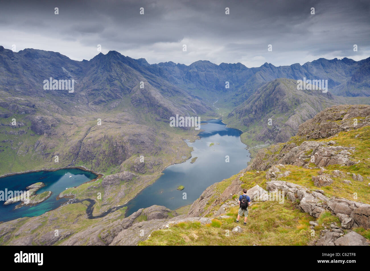 Male walker admiring the view over Loch Coruisk to the jagged ridge of the Black Cuillin mountains, Isle of Skye, Scotland Stock Photo