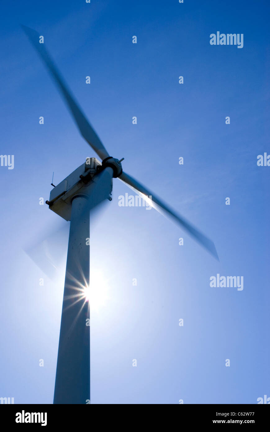 Spinning wind turbine with sun behind it Stock Photo