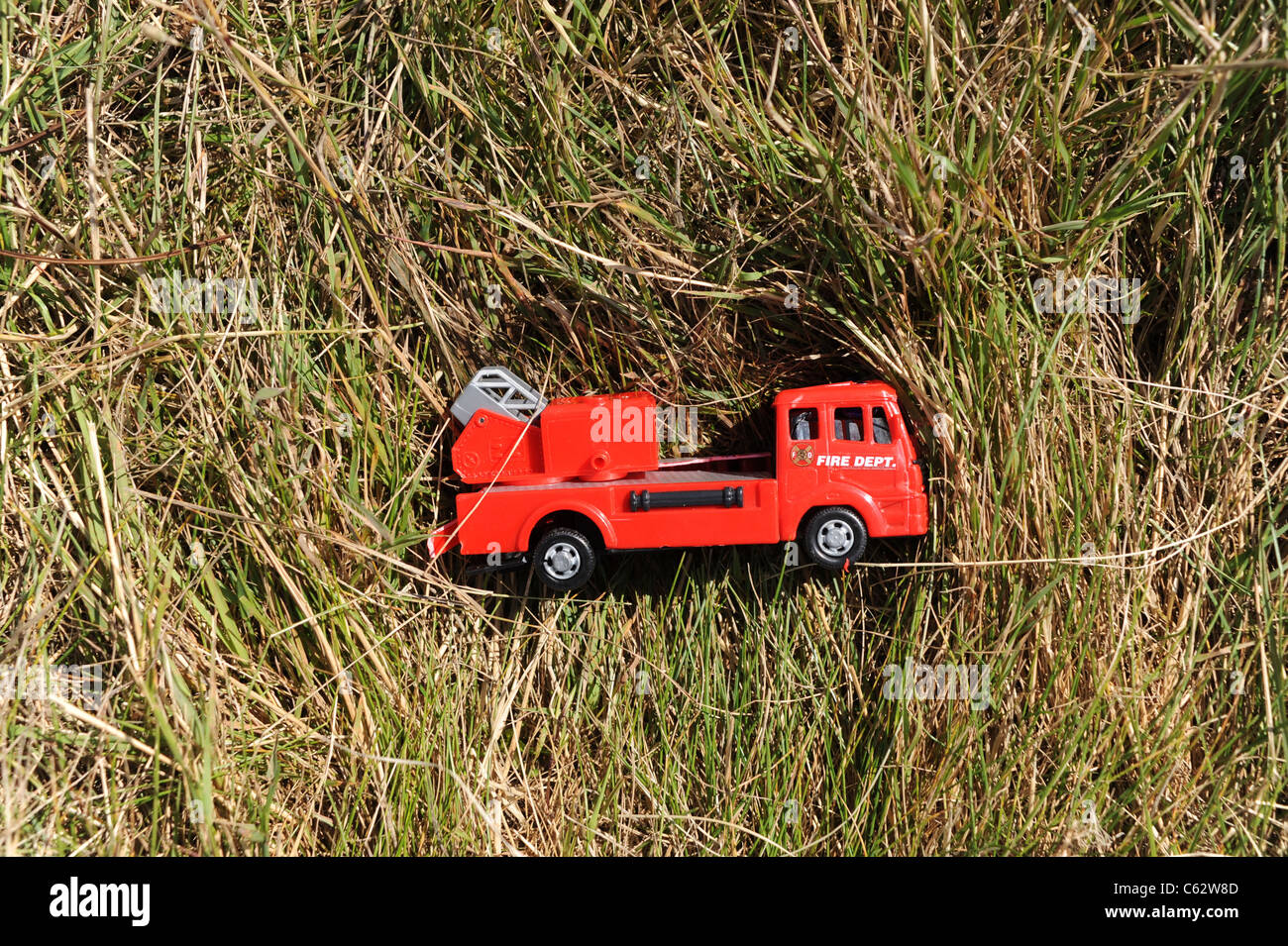 Toy fire engine lays in grass Stock Photo