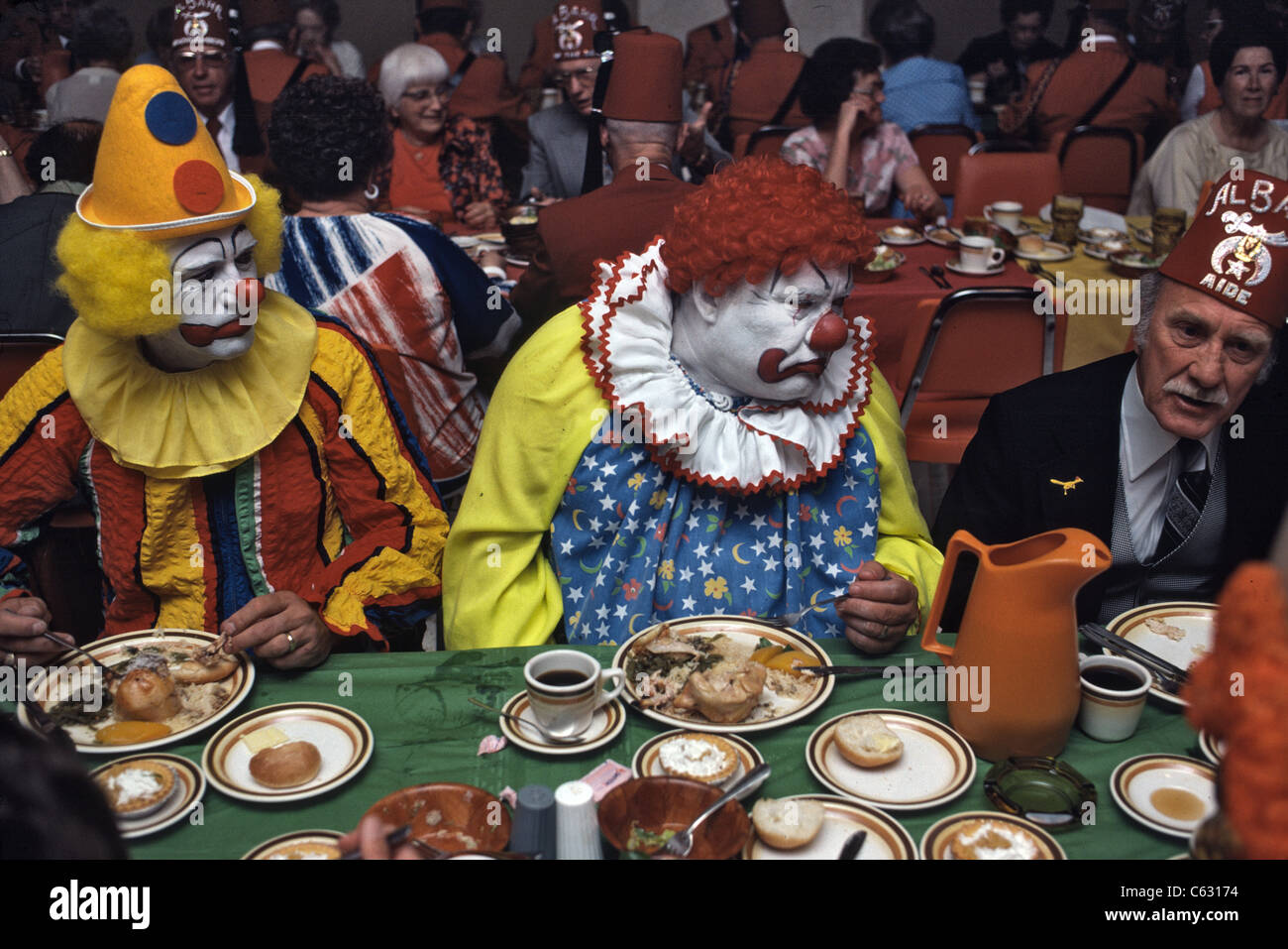 Shriners event with clowns in full make-up eating Stock Photo