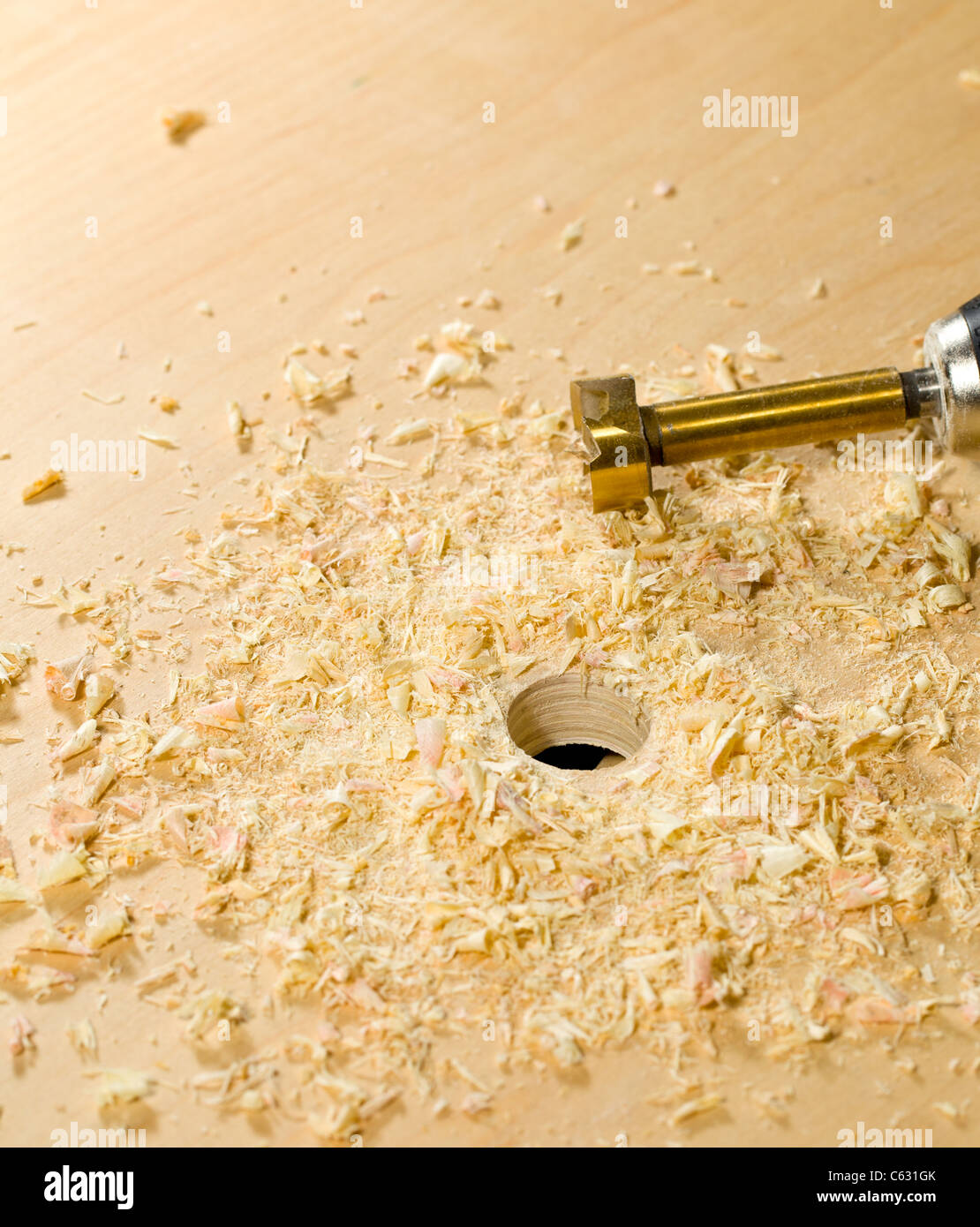 Drilling a large hole in a piece of plywood with a drill and bit Stock Photo