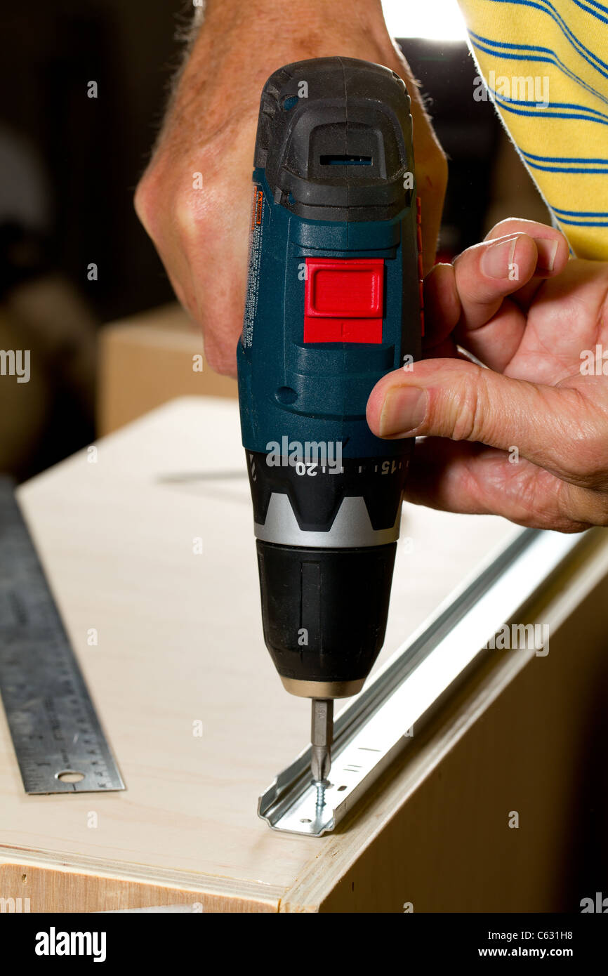 Screwing A Screw Into A Drawer Runner On Side Of Wooden Drawer