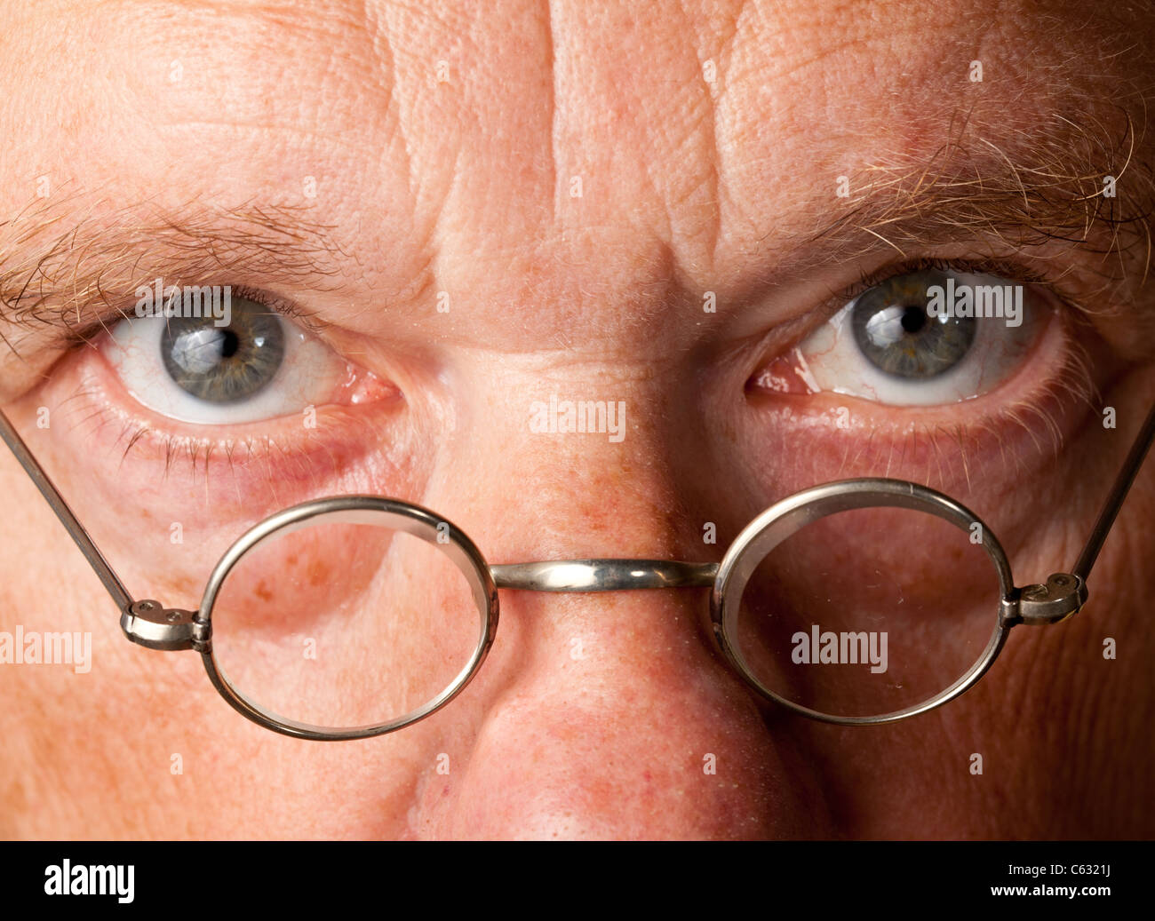 Portrait of a senior male with the focus on magnifying glasses and the eyes are in focus Stock Photo