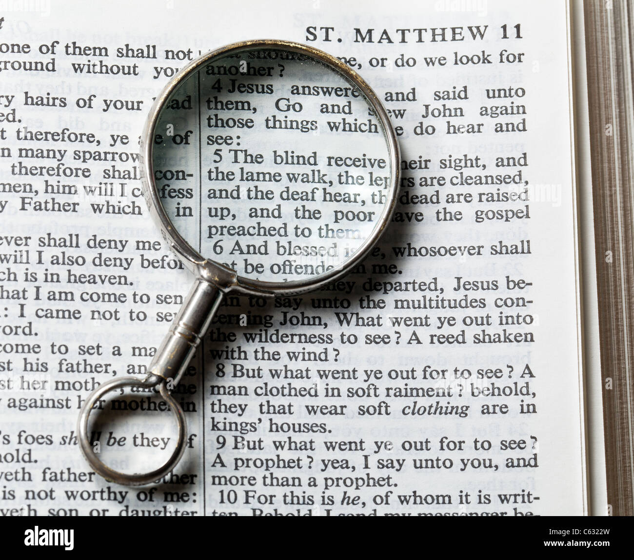 Antique brass magnifying glass over the top of an Authorized King James Bible on the paragraph about blind being able to see Stock Photo