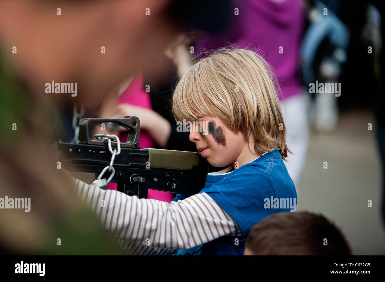 A boy holding a rifle at an army exhibition stand. Eastbourne, east Sussex. England, UK Stock Photo