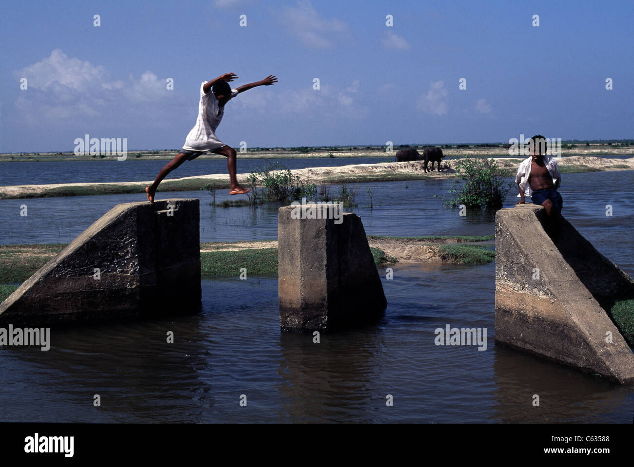 Two Tamil young boys play on a drainage canal along the coast in Jaffna, Sri Lanka. The island has suffered over 30 years of war Stock Photo