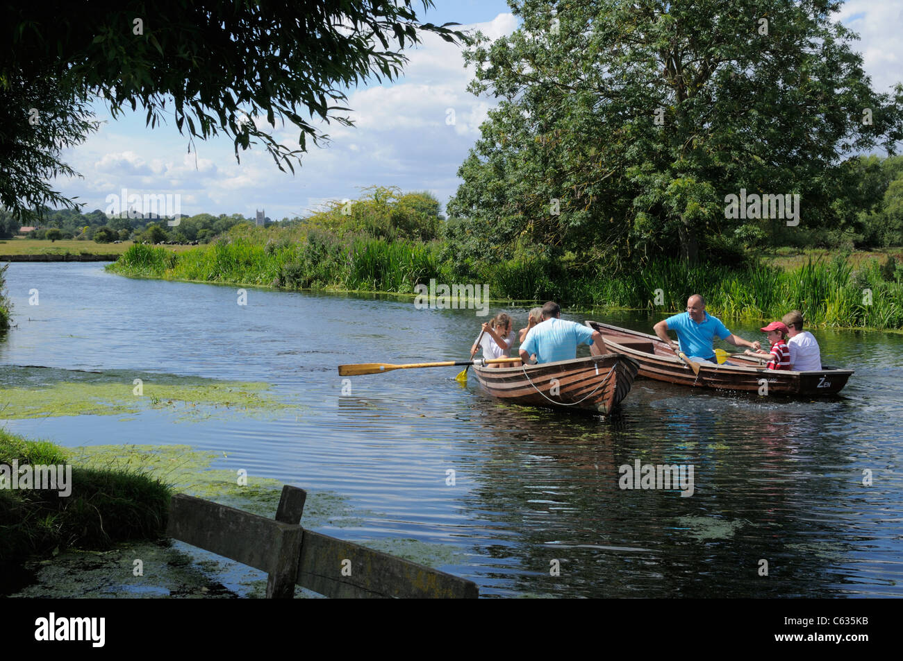 Two families boating in wooden rowing boats on the River Stour near