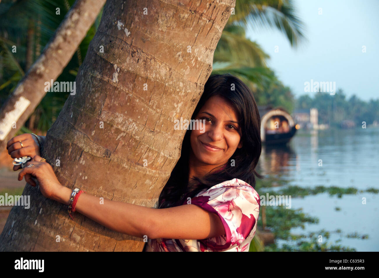 Portrait pretty girl hugging palm tree Kerala Backwaters South Inia Stock Photo