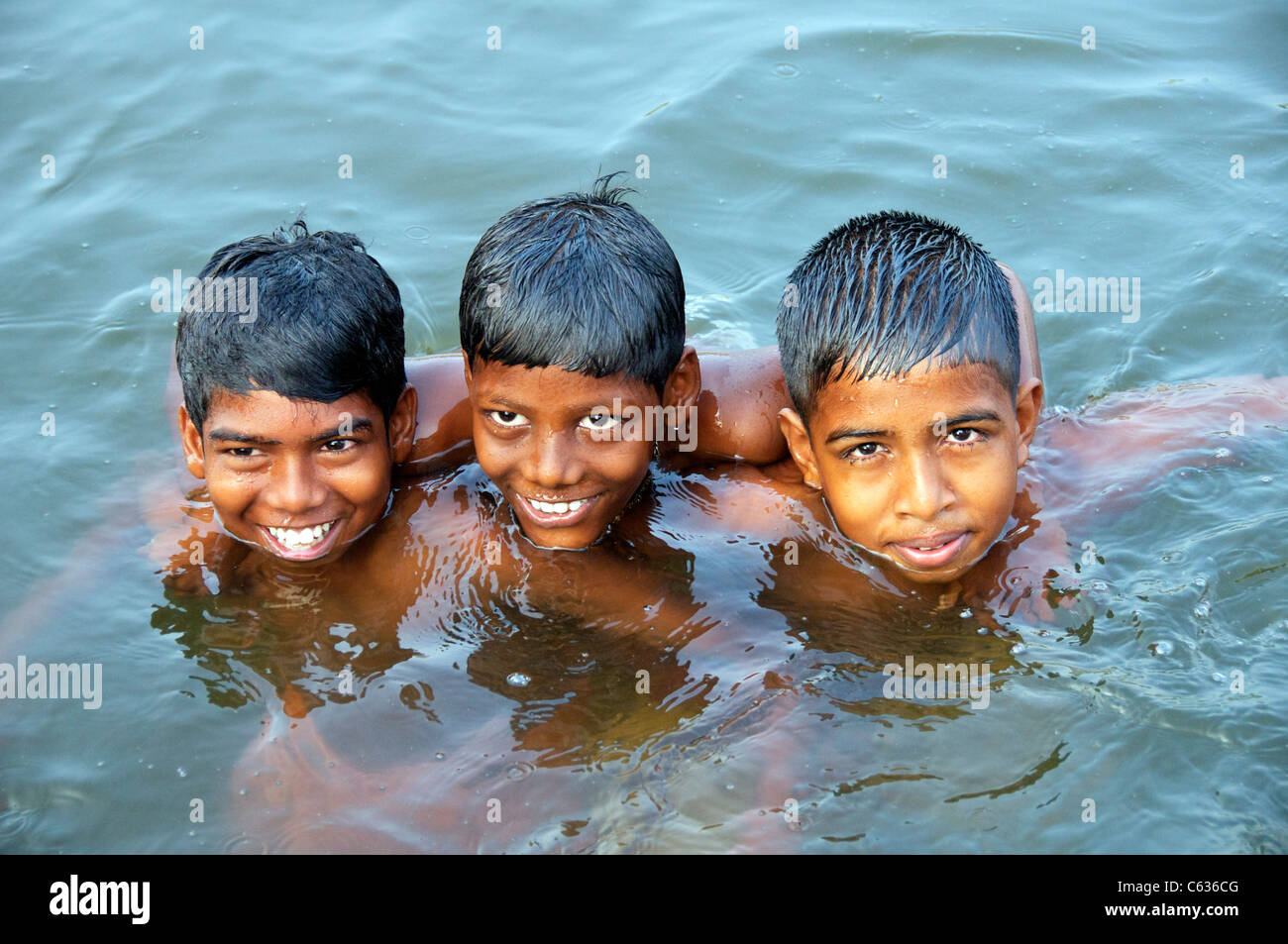 Three boys swimming in canal Backwaters Kerala South India Stock Photo