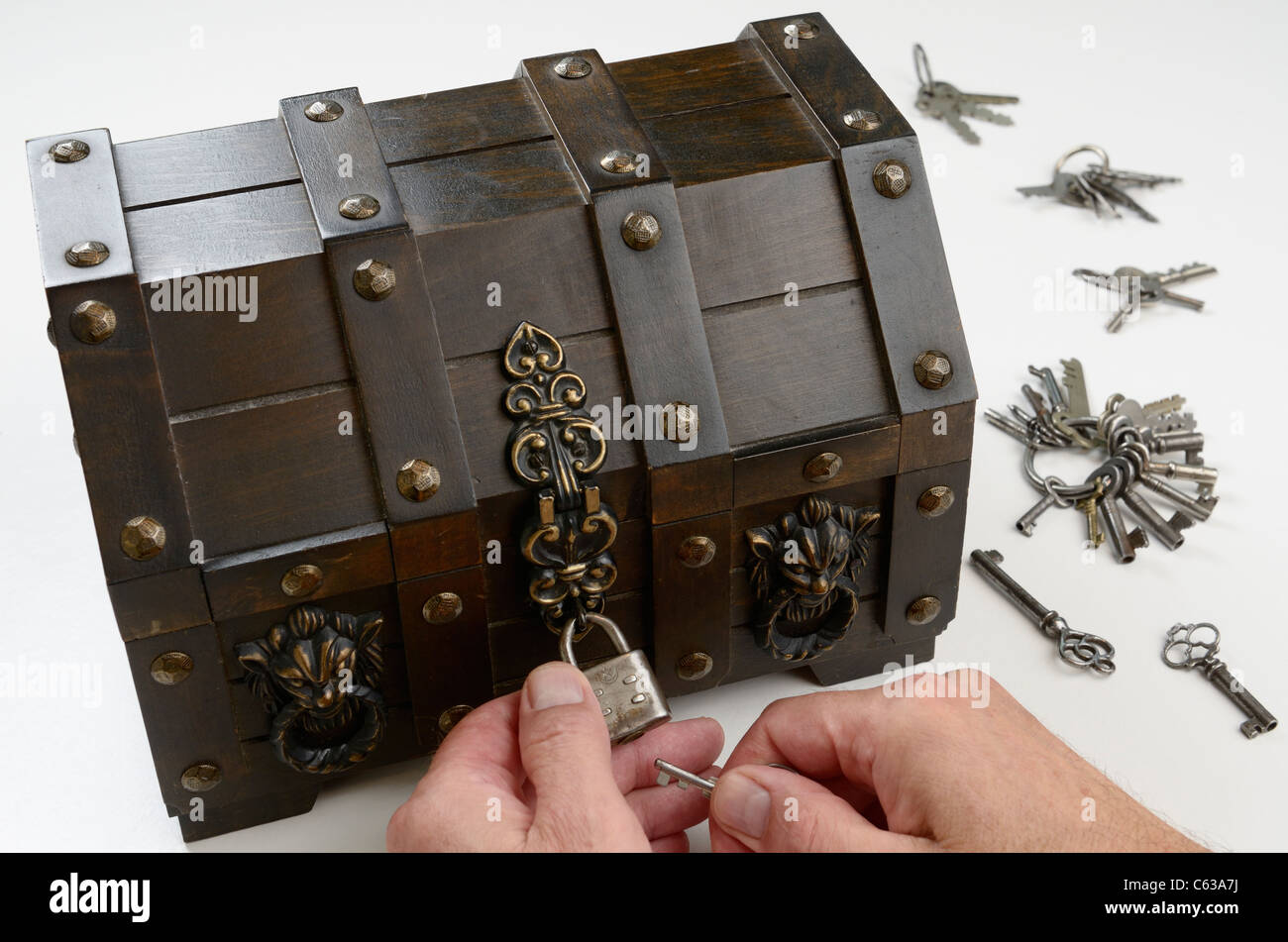 Man's hands searching for the key to fit the lock on a treasure chest Stock Photo