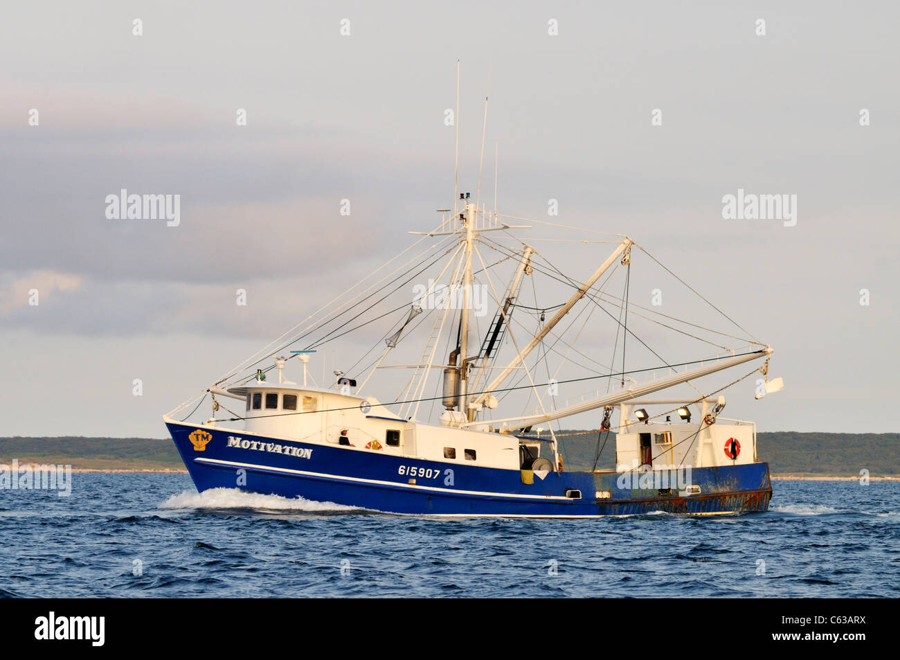 Blue hulled working fishing boat with outriggers out off the coast of Cape Cod, USA. Stock Photo