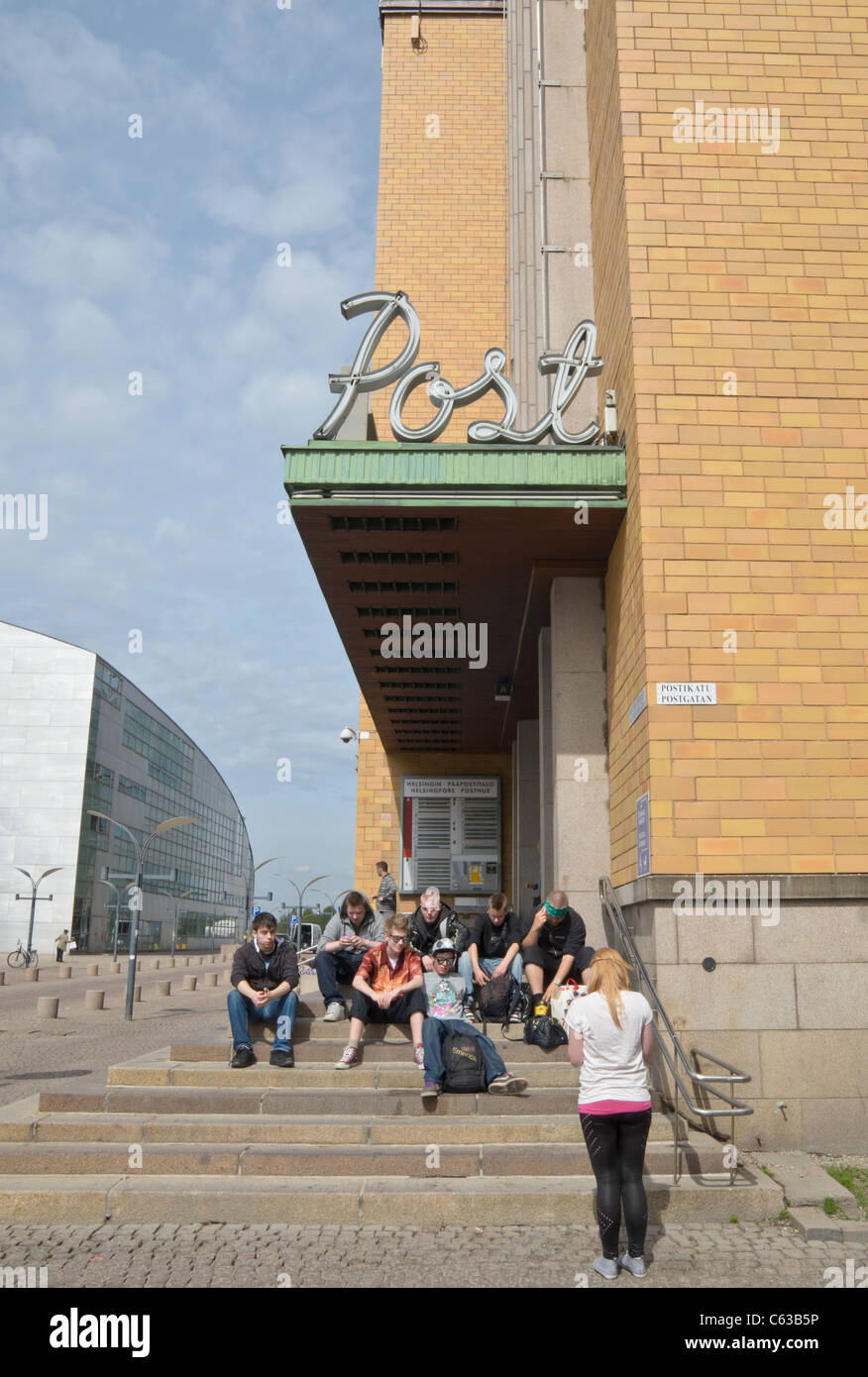 Finnish teenagers sitting on steps outside the main post office in Helsinki, Finland Stock Photo