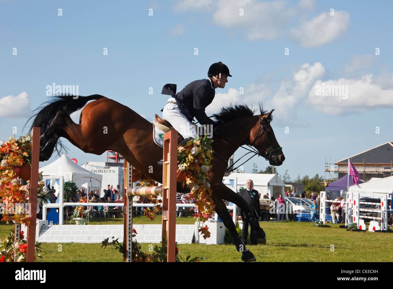 North Wales, UK. International show jumping event with horse and jockey jumping over jumps at Anglesey Show in Mona showground Stock Photo
