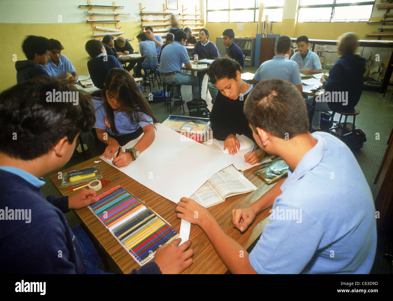 Study group with art materials at desk in elementary school classroom with teacher and students in Caracas, Venezuela Stock Photo