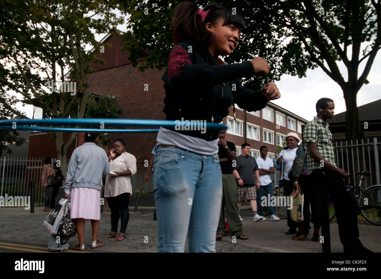 Clarence Road Hackney. Street tea party one week after the riots. Young girl playing with a hula hoop in front of estate Stock Photo