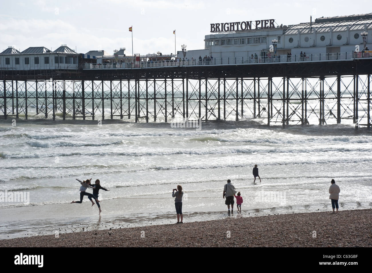 Brighton Pier with people playing in the waves Stock Photo