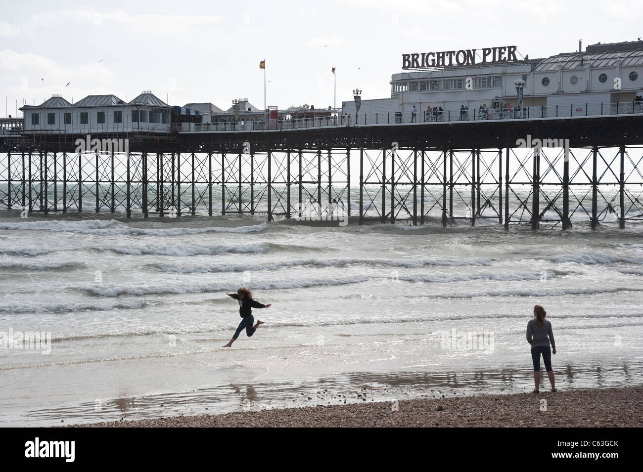 Brighton Pier with people playing in the waves Stock Photo