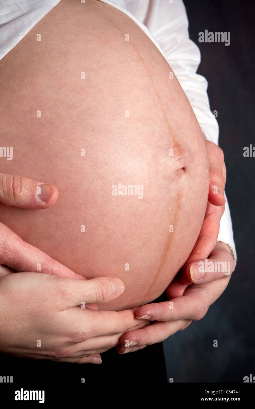 Man and woman hands hold the pregnant stomach of the unborn child. Stock Photo