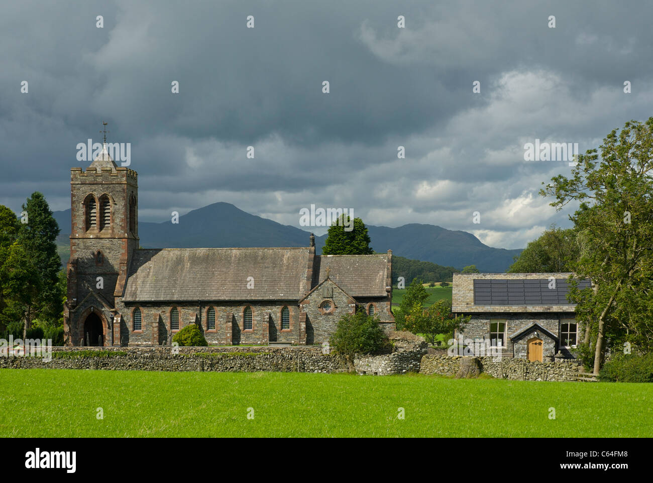 St Luke's Church, Lowick, Lake District National Park, Cumbria, England UK, with village hall fitted with solar panels Stock Photo
