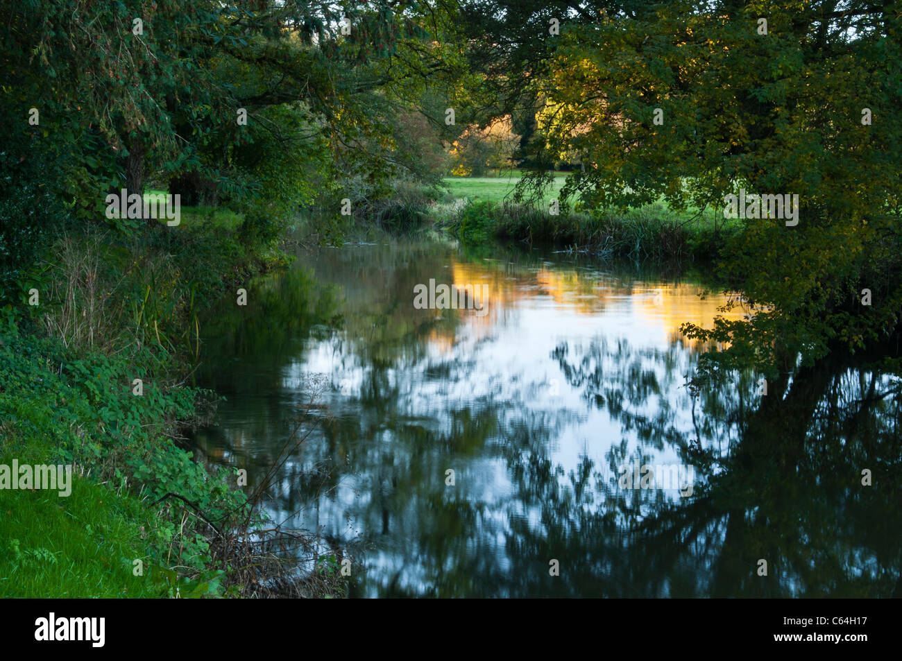 Autumn colours reflected in the River Cherwell which forms the boundary to the grounds of Rousham House in Oxfordshire, England Stock Photo