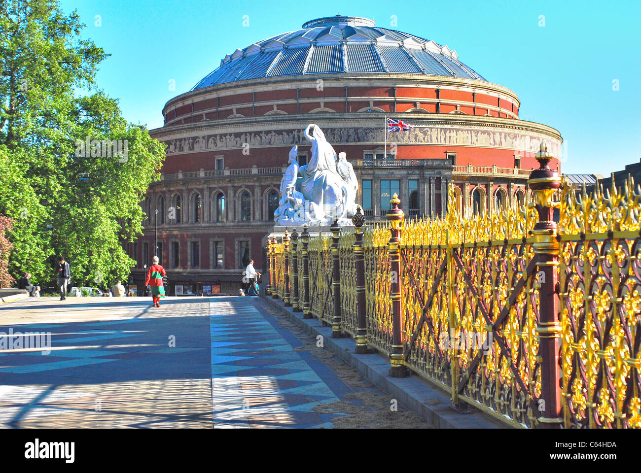 Royal Albert Hall, London, seen from east side of  the Albert Memorial on bright  Spring day with ornate railings lit up by sun. Stock Photo