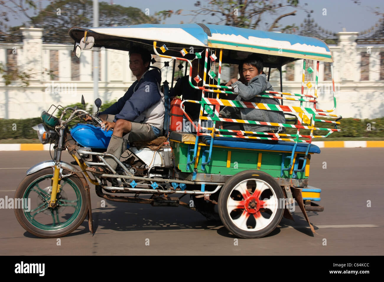 Laotian Jumbo  tricycle passenger rickshaw speeding through Vientiane, Laos Stock Photo