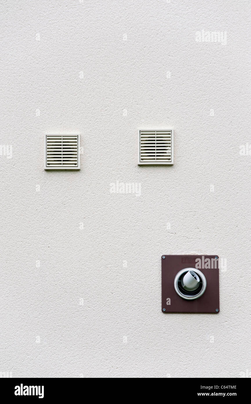 Wallmounted ventilation outlets and the flue from a gas boiler, on the outside wall of a modern