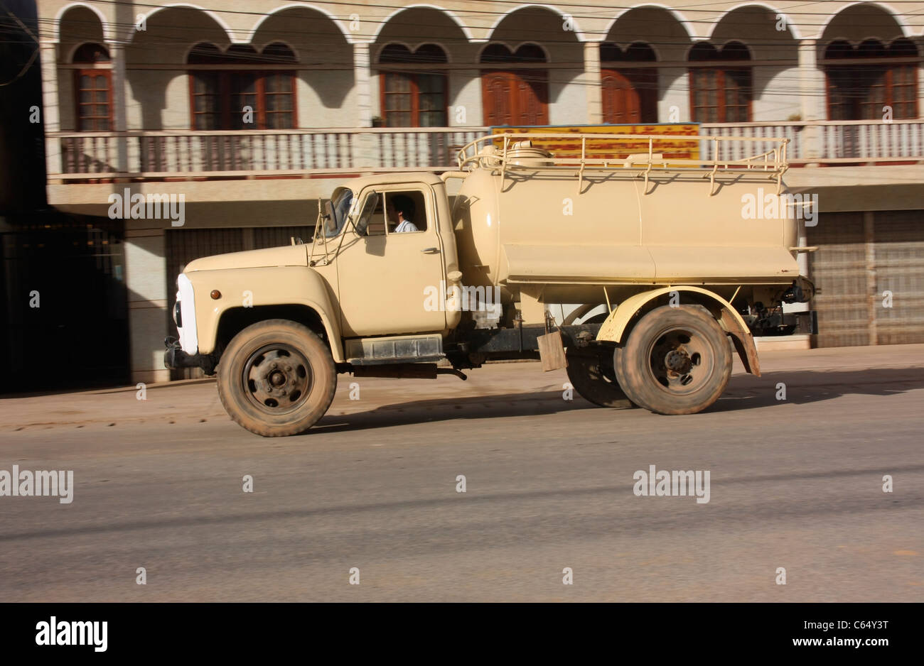 Russian manufactured ZIL130 water truck speeds through a town in northern Laos at sunset Stock Photo