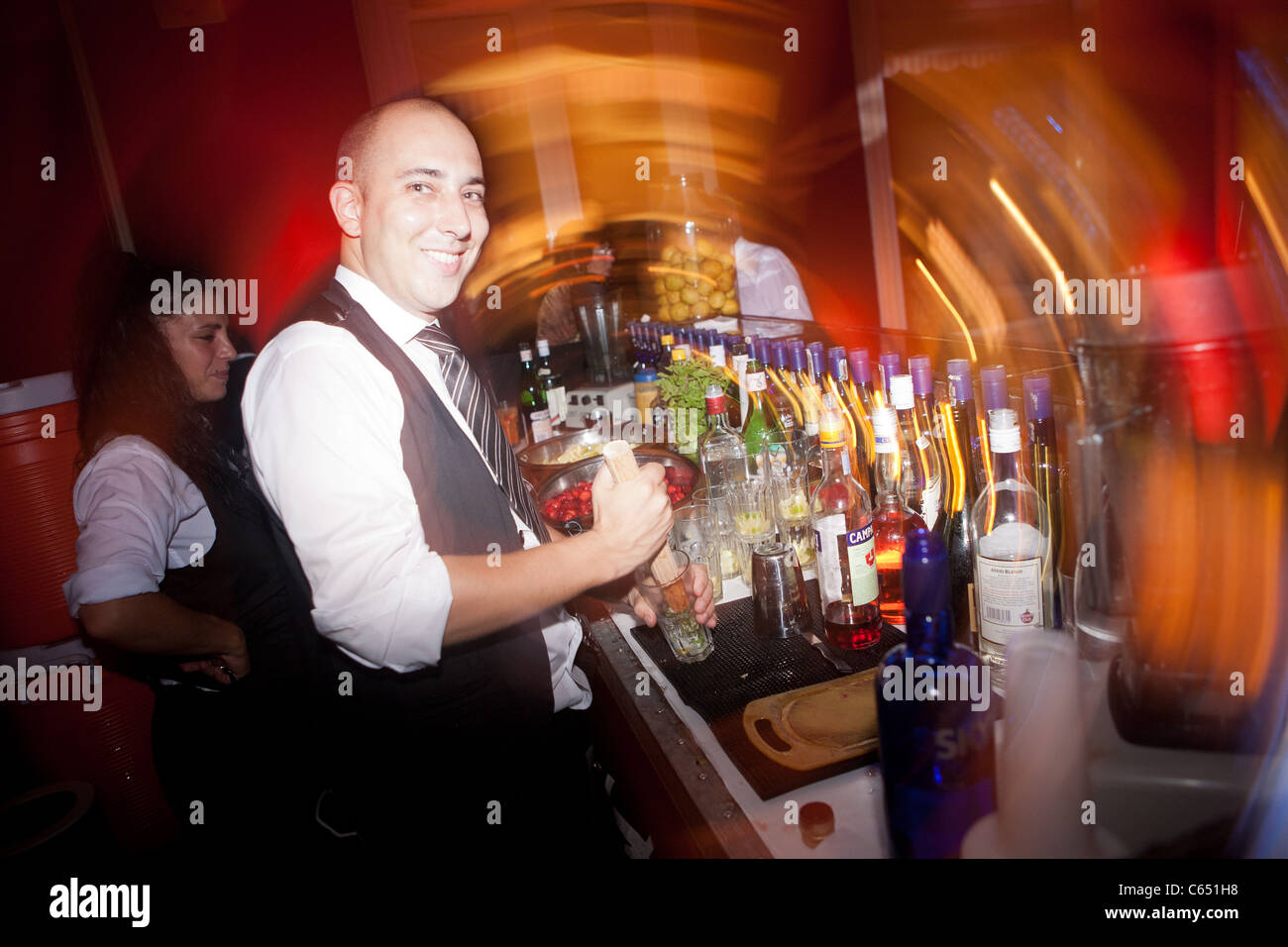 A bar tender in a bar preparing a drink and smiling with happiness Stock Photo