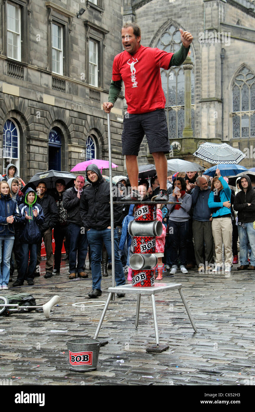Edinburgh Scotland busy city centre Fringe Festival performer on The Royal Mile in the city centre in the rain  balancing act Stock Photo