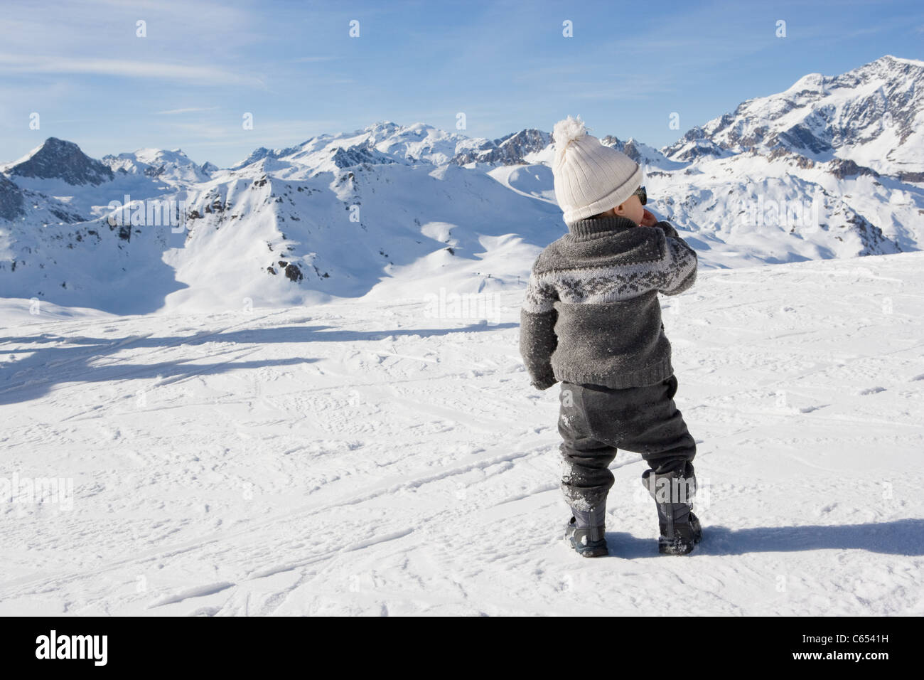 Young boy standing looking at mountains in snow Stock Photo - Alamy