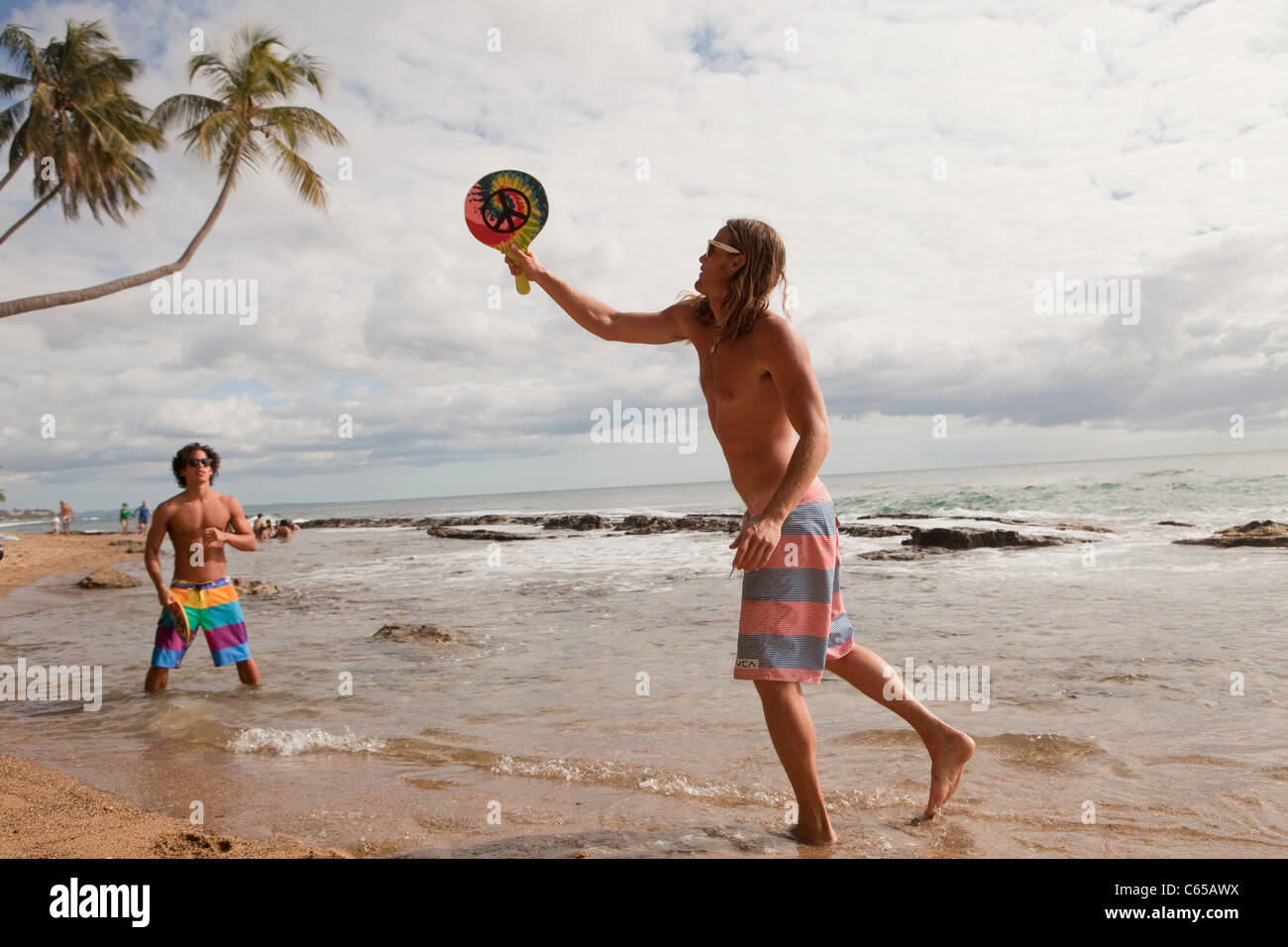 People on beach, men playing bat and ball game Stock Photo