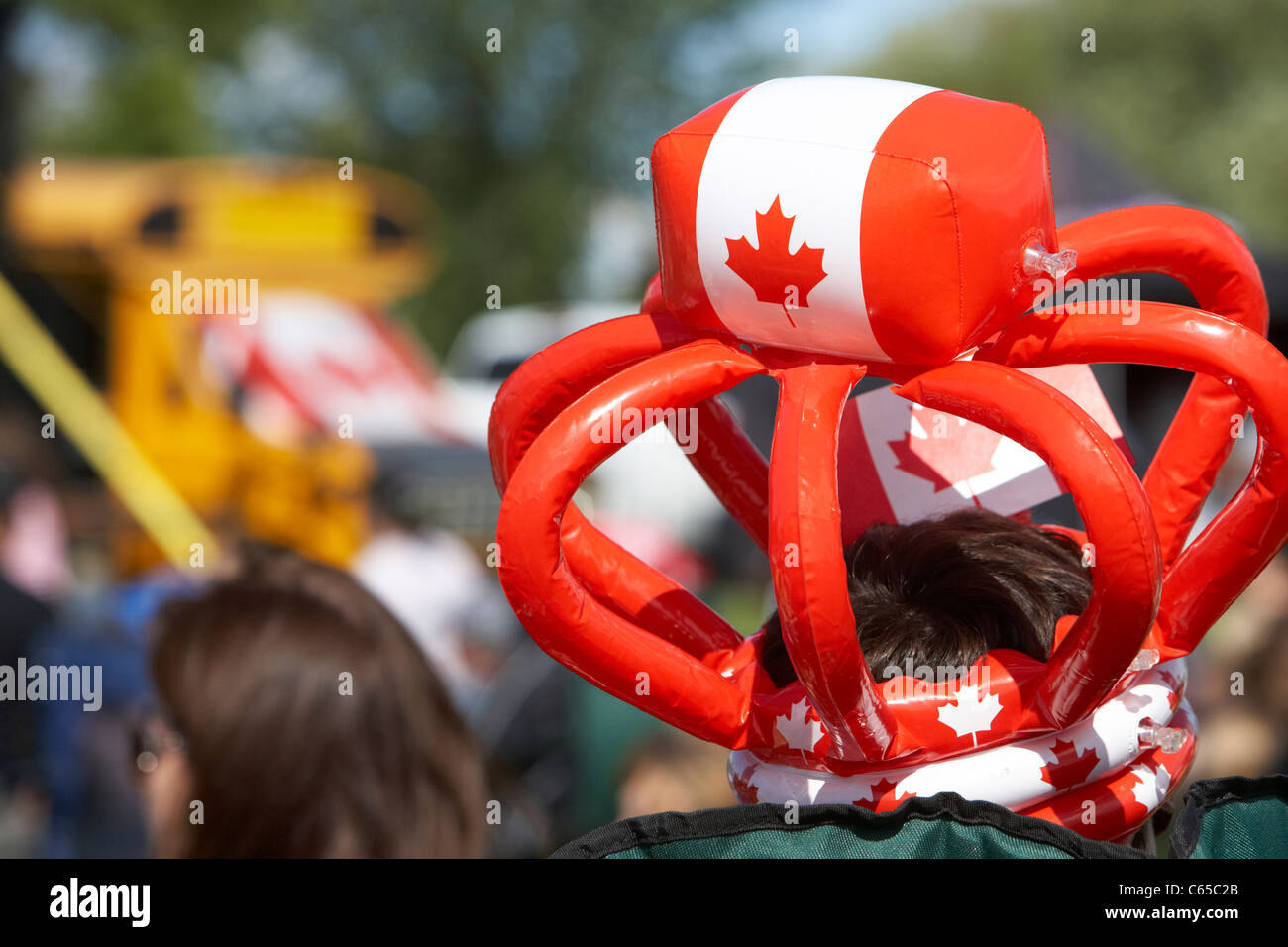 man wearing inflatable hat with maple leaf at festival on canada day Saskatoon Saskatchewan Canada Stock Photo