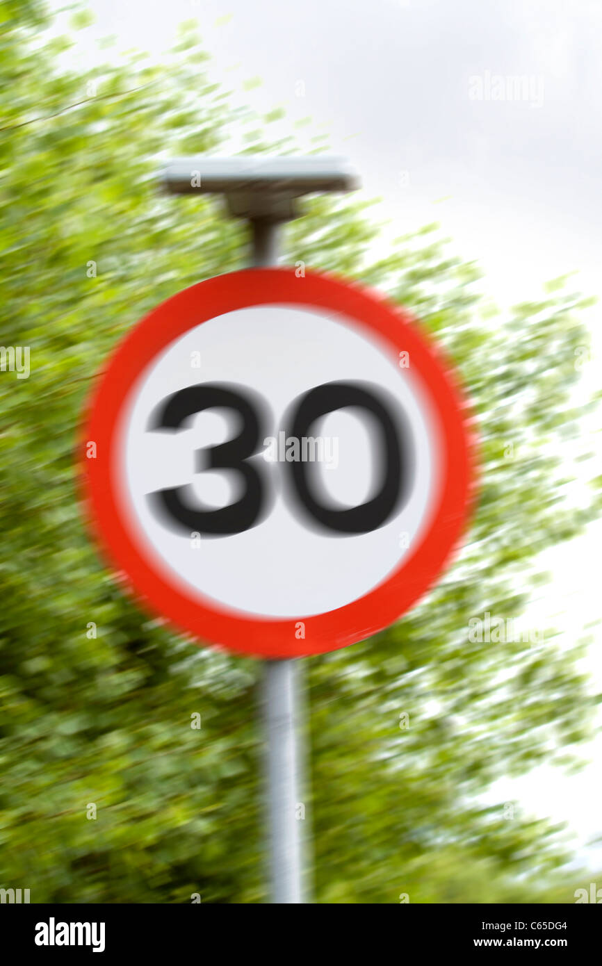 A 30 mph British speed limit sign showing movement to indicate excess speed Stock Photo