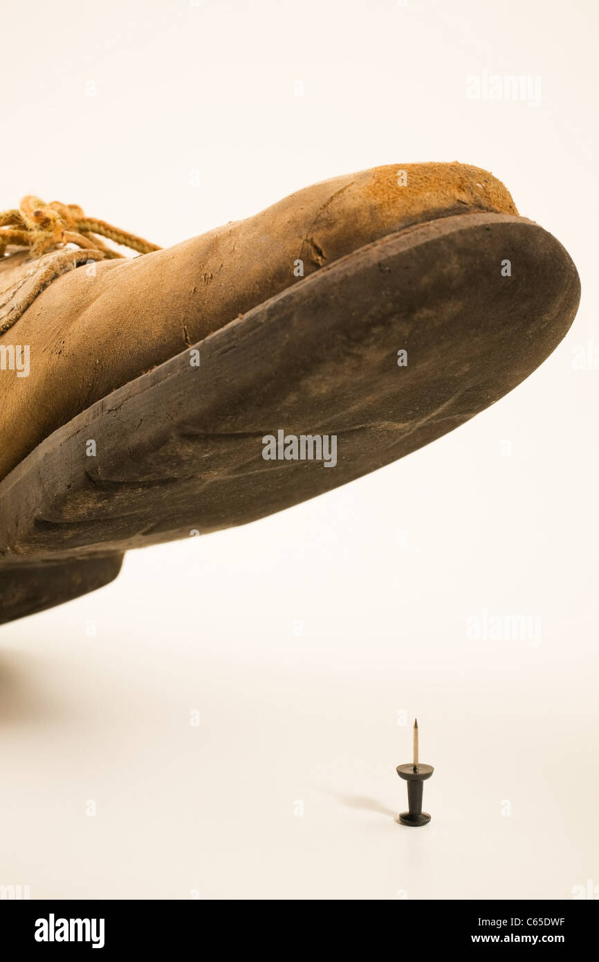 Shoe about to step on thumbtack Stock Photo
