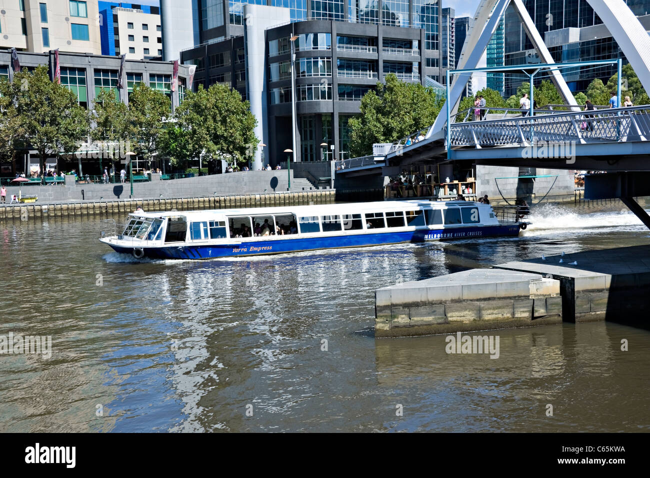 A Tourist Boat River Cruise Craft Passes Under The Yarra River Footbridge in Melbourne Victoria Australia Stock Photo