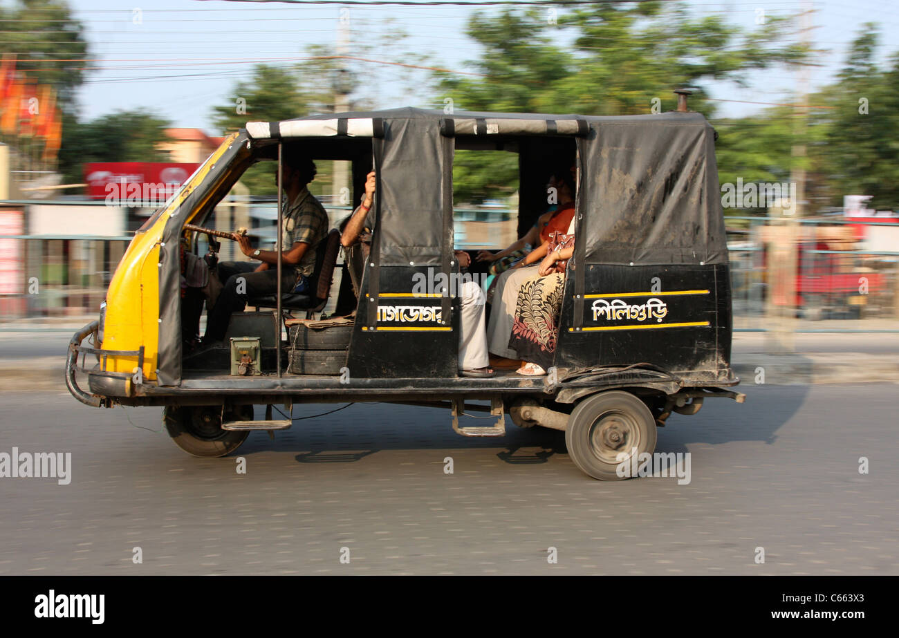 Three wheeler taxi bus races through Siliguri city streets in India Stock Photo