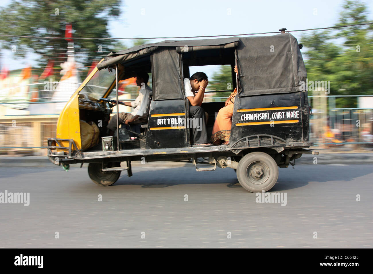 Three wheeler taxi bus races through city streets in India Stock Photo