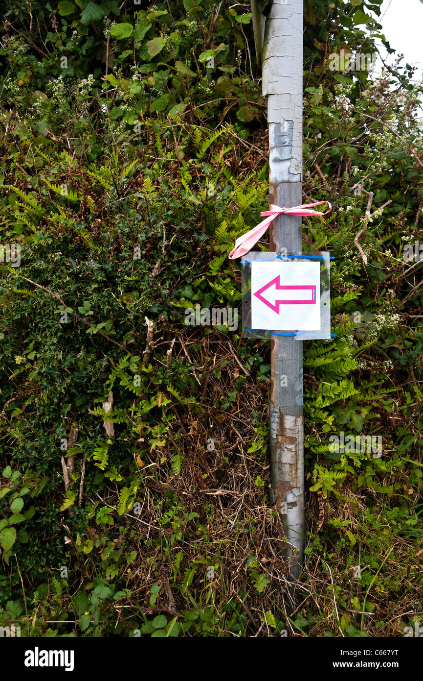 Arrow sign mounted on a street sign support post, directing traffic and/or pedestrians to the left, down a rural lane Stock Photo