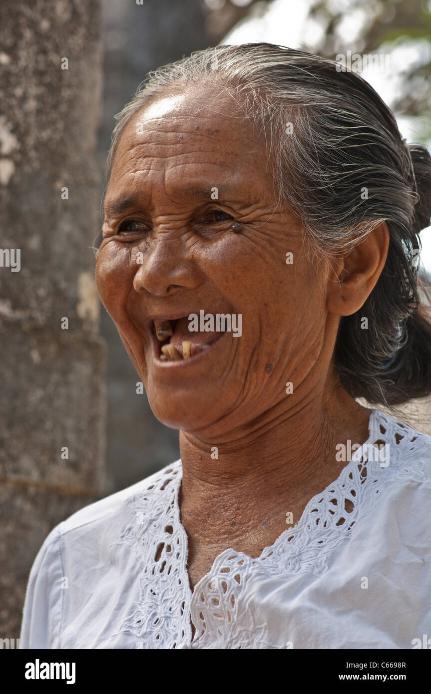 Head and shoulders shot of an elderly Balinese woman smiling with missing  teeth Stock Photo