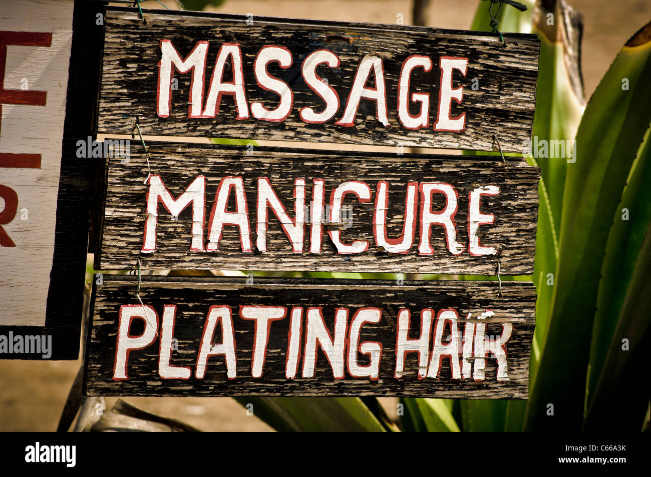 Closeup of a handmade, misspelt wooden sign on a beach hut in Bali. Massage, Manicure, Plating Hair. Stock Photo