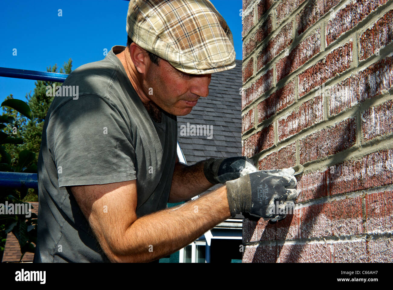 Stone mason smoothing shaping cement grout in brickwork repair Stock