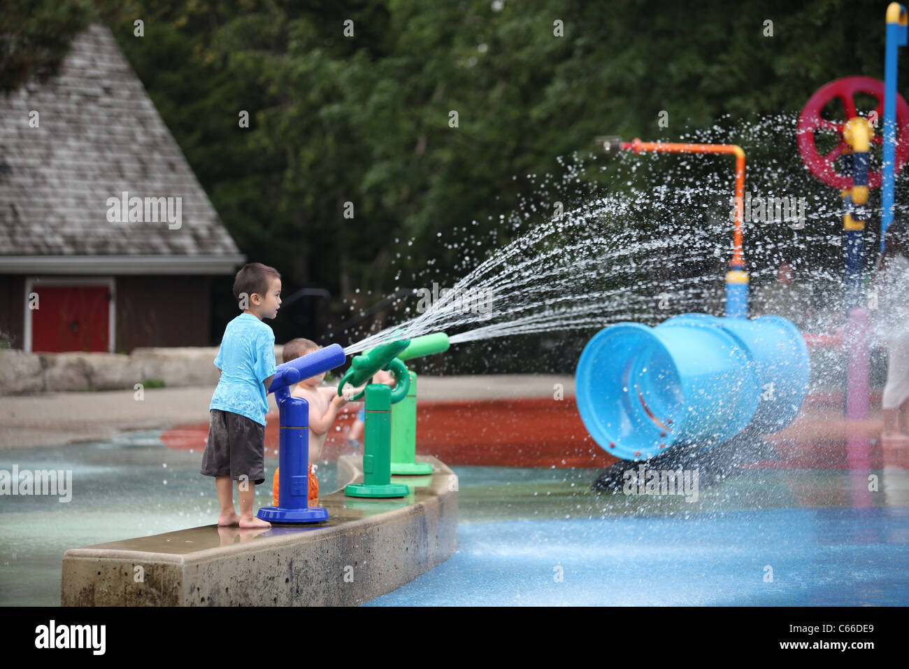 Boy shooting water gun at water park Stony Brook in summer Stock Photo