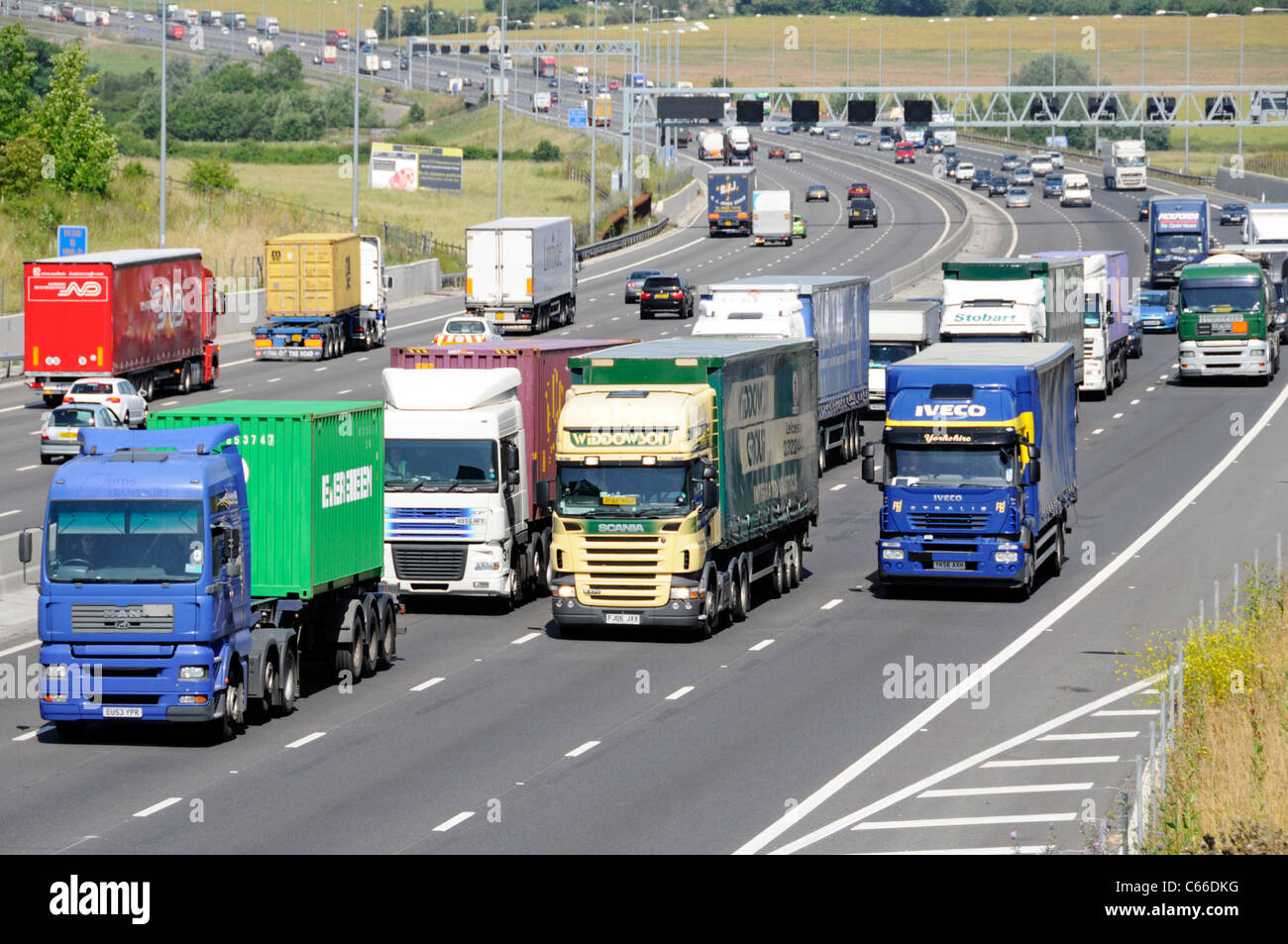 Transport lorry truck four lanes section of M25 motorway Essex countryside overtaking slower hgv lorries & trucks busy traffic on gradient England UK Stock Photo