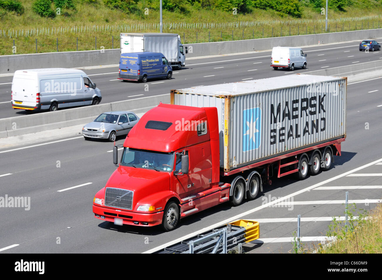 HGV Volvo lorry truck & articulated trailer loaded Maersk shipping container driving along motorway (company data removed from red lorry) England UK Stock Photo