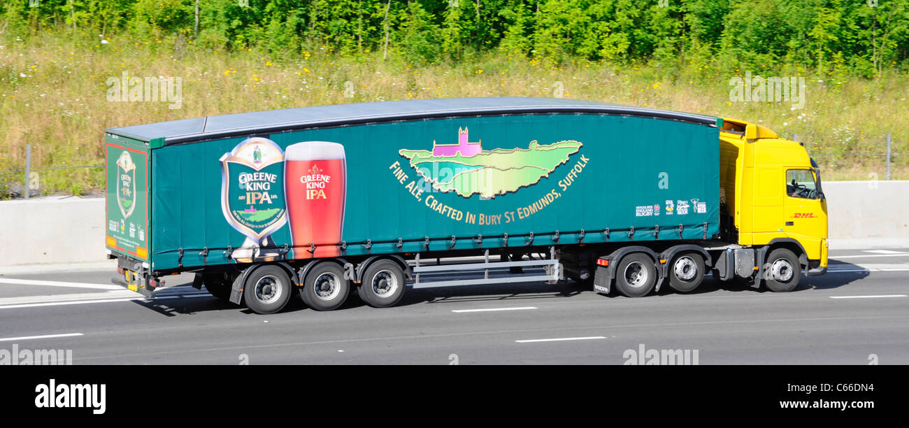 Greene King brewery business IPA beer supply chain advertising on articulated trailer behind a DHL hgv lorry truck driving along UK motorway Stock Photo
