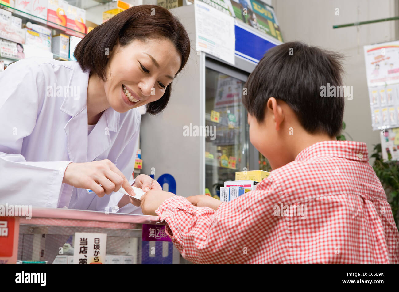 Pharmacist Talking to Boy at Drugstore Stock Photo